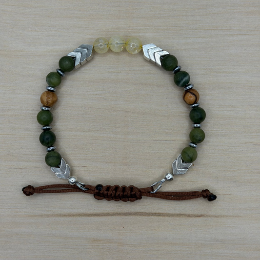 Bracelet with green, brown, and silver beads on a wooden surface